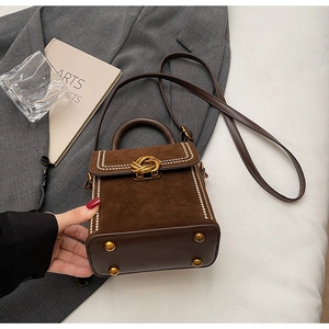 Détail du petit sac boîte en daim avec fermoir doré et surpiqûres blanches contrastées