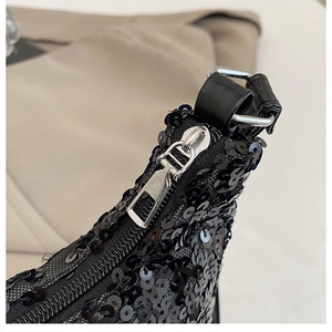 Detailed close-up of black sequin fabric with silver zipper and leather shoulder strap buckle
