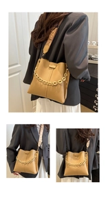 Detail of khaki leather bucket bag featuring gold chain and wide fabric shoulder strap