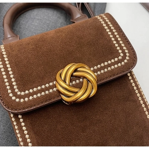 Détail d'un sac en daim marron avec broderie florale vintage et fermoir doré torsadé