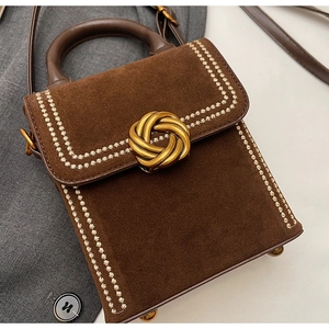 Détail du sac carré en daim marron avec fermoir doré et surpiqûres en forme d'étoile