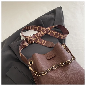 Detailed macro view of a brown lychee pattern bucket bag with chic chain and jacquard strap