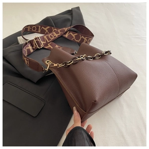 Detail of brown litchi pattern leather bucket bag with chain and jacquard strap