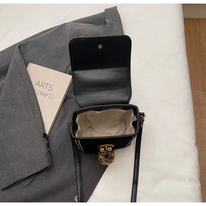 Detail view of open black matte flap bag showing beige fabric interior and gold twist lock