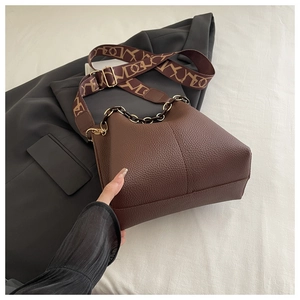 Detailed macro view of dark brown lychee grain leather texture and metallic chain handle