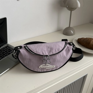 Light purple crescent shoulder bag with embroidery on a desk with accessories