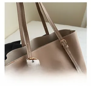 Détail du fourre-tout beige montrant la texture, la sangle et le ruban mode