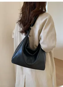 Minimalist black PU leather tote bag with vertical stitching shown on model shoulder