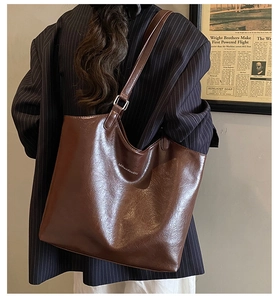 Detailed view of large dark brown leather tote bag with glossy finish and logo