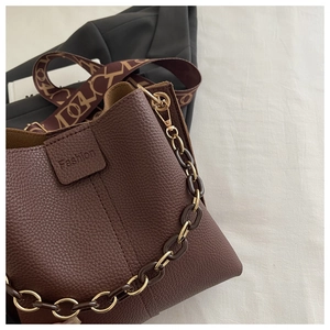 Detailed macro of brown lychee leather bucket bag with fashion label and vintage strap