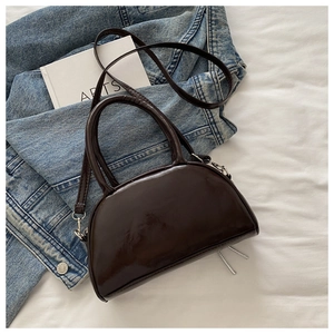 Détail du sac demi-lune en cuir verni marron foncé avec deux poignées et longue bandoulière