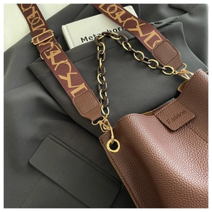 Macro shot of brown lychee leather bucket bag with jacquard strap and resin chain link detail