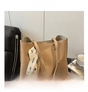 Détail du sac cabas en cuir beige avec une bandoulière en ruban tissé noir et blanc