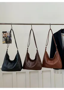 Close-up of minimalist leather hobo bags in black, dark brown, and caramel brown colors
