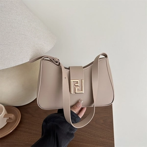 Elegante beige halbmondförmige Schultertasche mit goldener Schnalle auf Schreibtisch
