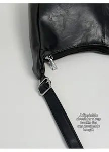 Close-up of black leather tote bag showing smooth zipper and adjustable metal strap buckle