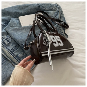 Détail du sac à main en cuir verni marron foncé avec numéro 95 et chaîne argentée