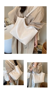 Detail of glossy beige oversized tote bag showing logo embossing and reflective finish