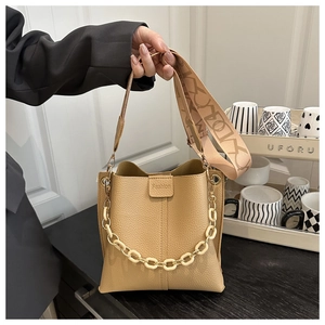 Detail of lychee pattern leather bucket bag with chunky chain and woven strap