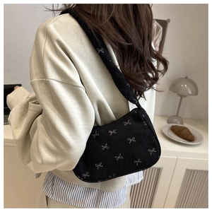 Detail of black corduroy shoulder bag with silver bow print and soft ribbed texture