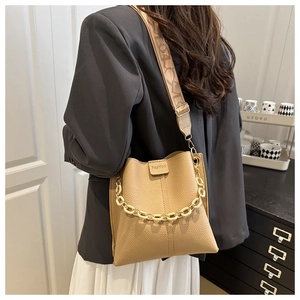 Detail of beige lychee leather bucket bag with retro patterned strap and chain