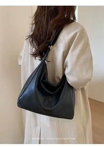 Close-up of minimalist black PU leather tote bag with silver buckle and adjustable strap