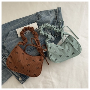 Flat lay of corduroy bow shoulder bags in brown and green with ruffled cloud handles