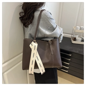 Détail d'un sac cabas marron foncé avec surpiqûres blanches et ruban tendance