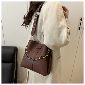 Close-up of a dark brown litchi pattern bucket bag with a stylish chain and fabric strap