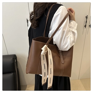 Détail d'un cabas en cuir marron avec surpiqûres blanches et ruban imprimé mode