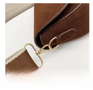 Détail du crochet en métal doré et de la bandoulière tissée du sac marron