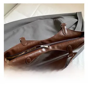 Detail of silver zipper closure and glossy dark brown leather on the tote bag