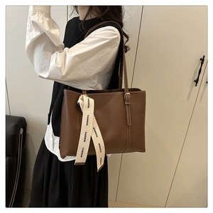 Détail d'un grand sac cabas marron en similicuir avec bandoulière à logo et boucle