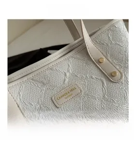 Detail of white tote bag featuring floral embroidery and golden metallic rivets