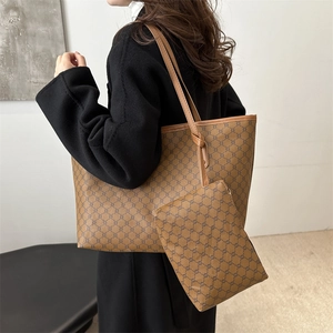 Detailed view of brown monogram tote bag set with matching small zipper pouch on a shoulder