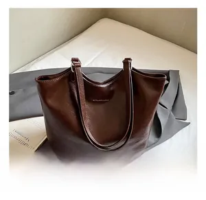 Detailed view of dark brown tote bag with glossy wrinkled texture and slim shoulder straps