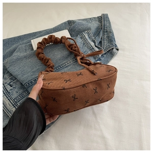 Detail of vintage brown corduroy shoulder bag with black bow print and ruched cloud handle