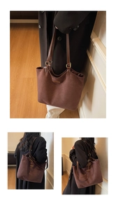 Detail of a large brown suede tote bag with gold trim and leather shoulder straps