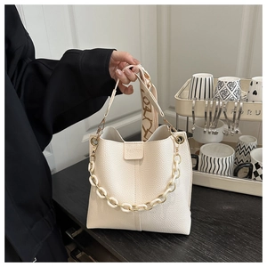Detail of off-white lychee leather bucket bag with fashion label and thick resin chain