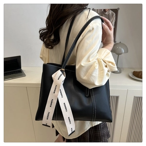 Détail d'un cabas en cuir noir avec surpiqûres blanches et ruban décoratif fashion
