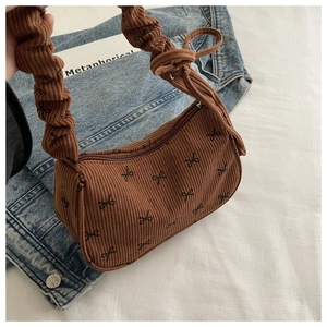Brown corduroy shoulder bag with black bow pattern and ruched handle detail