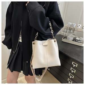 Detailed macro view of white pebble textured leather bucket bag with chain strap