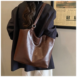 Detail of dark brown faux oil wax leather tote bag worn by model in vintage style