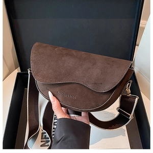 Detail of dark brown saddle bag featuring wide shoulder strap and debossed logo texture