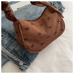 Detail of corduroy shoulder bag featuring bow patterns and a twisted handle design