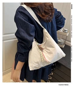 Vue détaillée du sac bandoulière blanc avec breloque peluche et cordon tissé