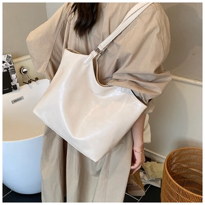 Close-up of a large cream leather tote bag with an adjustable wide shoulder strap for women