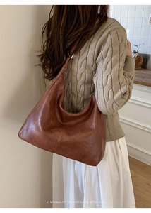 Detail of a brown leather hobo bag with a minimalist retro vibe and stitching detail