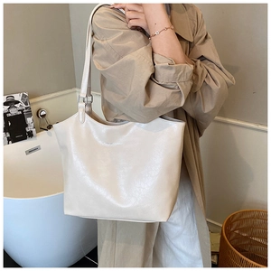 Detail of a cream-white leather tote bag with fine texture and slim double shoulder straps