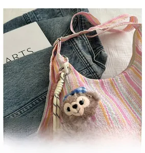 Gros plan d'un charme d'ours en peluche avec nœud bleu sur un sac cabas rayé